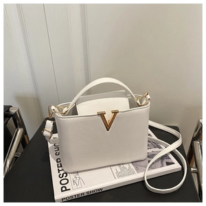 Close-up of white crossbody bucket bag with gold V-shaped hardware and litchi grain texture