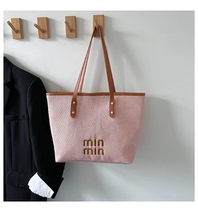 Detailed texture of pink woven fabric tote bag with brown leather straps and embroidery
