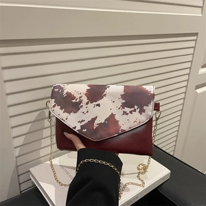 Classic cow print flap crossbody bag with premium brown leather and gold chain strap