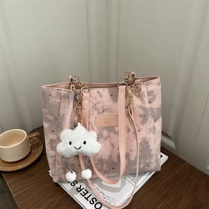 Pink tote bag with star moon pattern, chain strap and cloud plush charm on desk