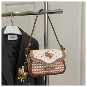 Detail of retro apple print crossbody bag with polka dot flap and bear plush charm