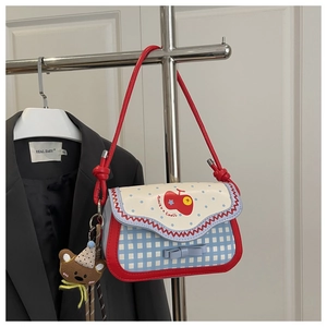 Detail of pink apple bag with blue polka dot flap, cherry print and teddy bear charm