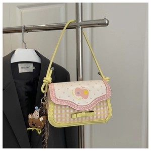 Detail of pink plaid bag with cute teddy bear charm and yellow bow on a metal hanger