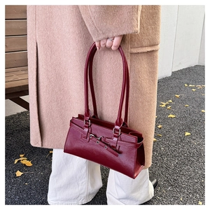 Detailopname van een vintage bordeauxrode handtas op een lichtbruine wollen jas in de herfst