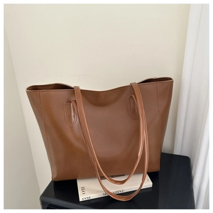 Close-up of minimalist brown faux leather tote bag with elegant shoulder straps for commuting