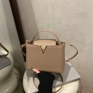 Minimalist V-shaped light brown bucket bag with lychee grain texture and gold metal buckle