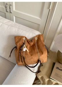 Detail of vintage brown suede tote bag featuring baseball charms and gold chain strap