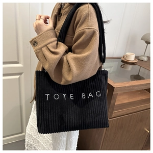 Detail of black corduroy tote bag with TOTE BAG embroidery and long shoulder strap