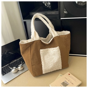Close-up of large suede tote bag with white sherpa trim on a minimalist workspace desk