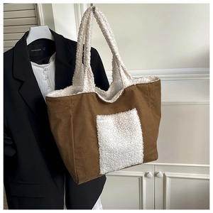 Detail of a large brown canvas tote bag featuring white faux shearling trim and pocket