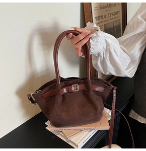 Detail of dark brown suede handbag with leather handles and decorative belt buckle
