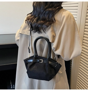 Detail of black matte handbag showing leather straps, metal buckle and textured material