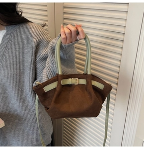 Detailed view of suede shoulder bag with green top handle and decorative buckle