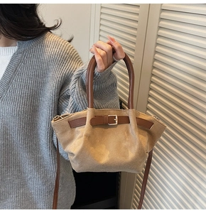 Detail of beige faux suede handbag with dark brown leather handles and metal buckle