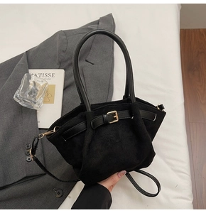 Detail of black matte suede mini basket bag with buckle strap on an urban fashion backdrop