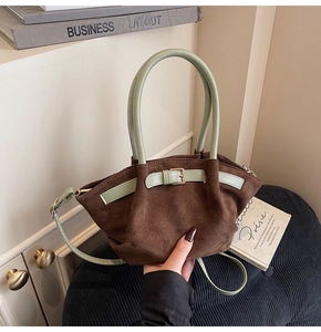 Close-up of brown suede handbag with mint green handle and elegant metal buckle detail