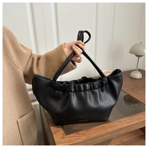 Detail van een zwarte leren handtas met elegante geplooide details en een slanke handgreep