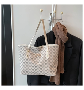 Détail du sac cabas beige avec jacquard à motif M et nœud doré élégant