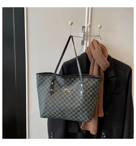Détail du motif monogramme avec nœud doré sur un grand sac cabas élégant