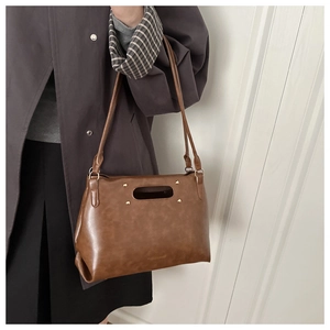 Close-up of brown vintage leather bag featuring four gold studs and long hollow handles
