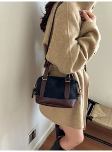 Detail of retro crossbody bag with black suede and brown leather trim on a model