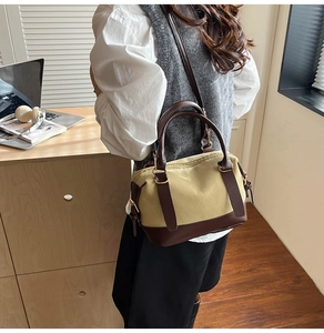 Detail of khaki canvas and brown leather crossbody bag styled on a female model