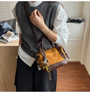 Detail of vintage bicolor tote bag in mustard frosted leather with teddy bear charm