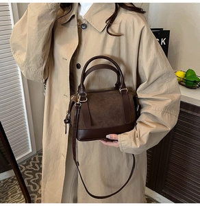 Détail d'un sac Boston marron foncé en cuir porté avec un trench-coat beige élégant