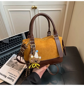 Detail of retro mustard suede and brown leather patchwork bag with small bear pendant
