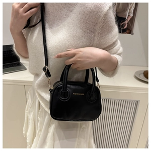 Detail of a black leather crossbody bag with gold text on white knit clothing