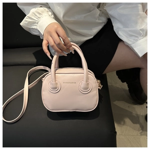Detail of light pink mini crossbody bag with embossed logo on black leather background