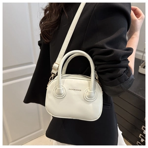 Détail du sac bandoulière en similicuir blanc avec imprimé sur un blazer noir