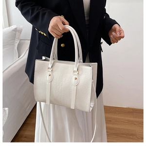 Close-up of white crocodile pattern tote bag with gold hardware and dual top handles