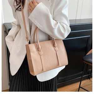 Detail of elegant beige crocodile pattern tote bag with dual handles and shoulder strap