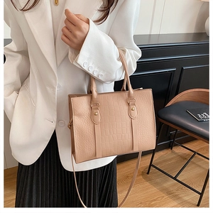 Detailed view of beige crocodile embossed tote bag with gold studs and slim shoulder strap