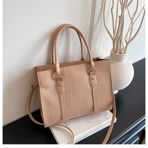 Detail of beige crocodile pattern leather tote bag on minimalist display setup