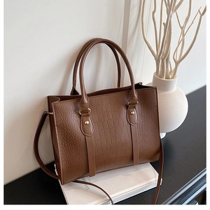 Detailed close-up of brown crocodile texture tote bag with elegant gold button accents
