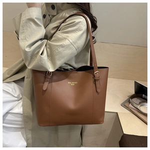 Detail van caramelbruine leren shopper met verstelbare gouden gesp en het merklogo erop