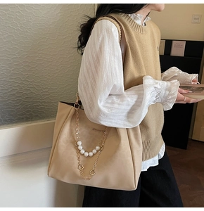 Gros plan détaillé d'un sac cabas beige avec perles décoratives et chaîne dorée chic