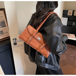 Sac sous le bras rétro marron avec fermoir rotatif argenté porté par un mannequin