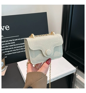 Détail du mini sac bandoulière vert menthe en daim avec couture vague et chaîne dorée