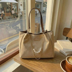 Grand sac cabas beige en daim avec chaîne de perles et poignées brunes au soleil