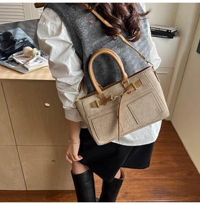 Detail view of canvas and leather crossbody bag with gold hardware on a model