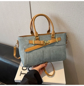 Detail view of vintage-style blue matte handbag featuring dual front pockets and metal buckles