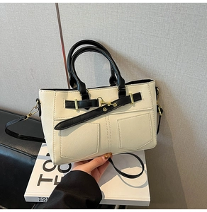 Detail of cream crossbody bag with denim pocket design and black contrast handles