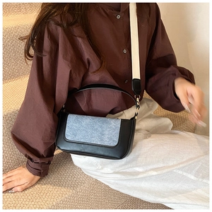 Dettaglio borsa retrò in pelle nera e patchwork denim blu con tracolla in tessuto largo