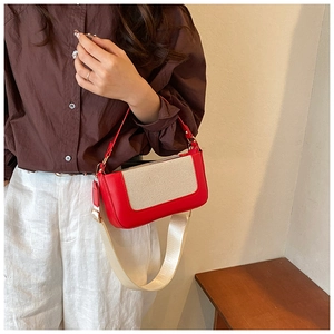 Dettaglio borsa a contrasto in pelle rossa e tela beige con tracolle regolabili