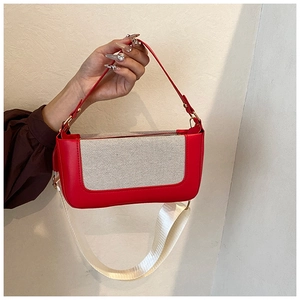 Dettaglio della borsa sottobraccio in pelle rossa e tela con tracolla larga rimovibile