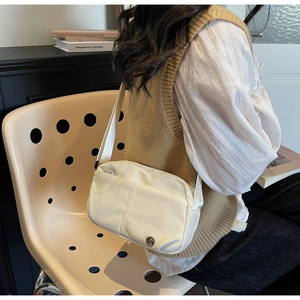 Detailed view of cream nylon crossbody bag with adjustable strap worn by a model