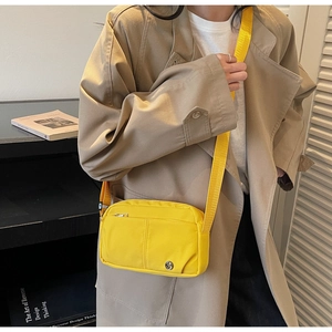 Close-up of bright yellow nylon crossbody bag featuring vertical stitching and adjustable strap